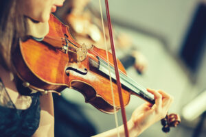 Symphony orchestra on stage, hands playing violin