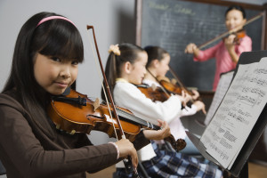 Asian girl playing violin in music class